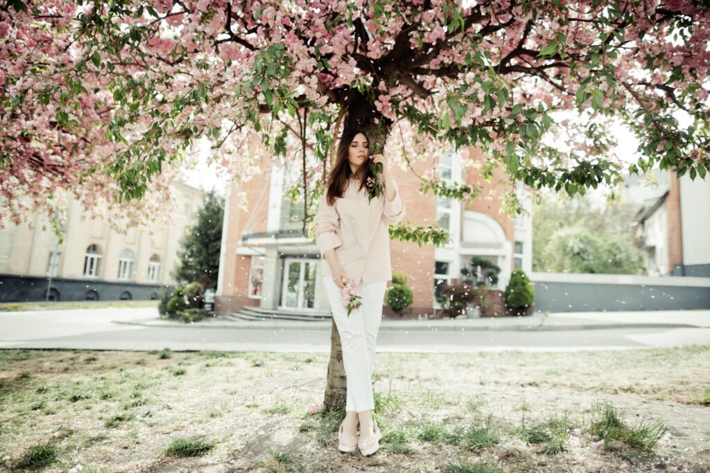 girl stands near a sakura tree on building background